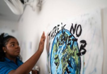 Student fixing in the wall a poster about environmental issues - There is no planet B