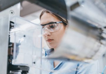 Professional young industrial factory woman employee working with machine parts putting, checking and testing industrial equipments cables in large Electric electronics wire and cable manufacturing plant factory warehouse