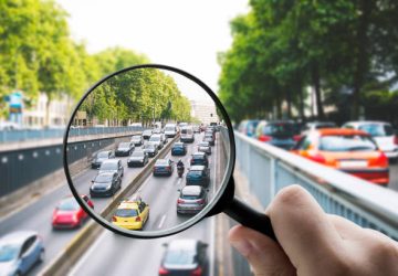 A magnifying glass over a traffic jam in a city.